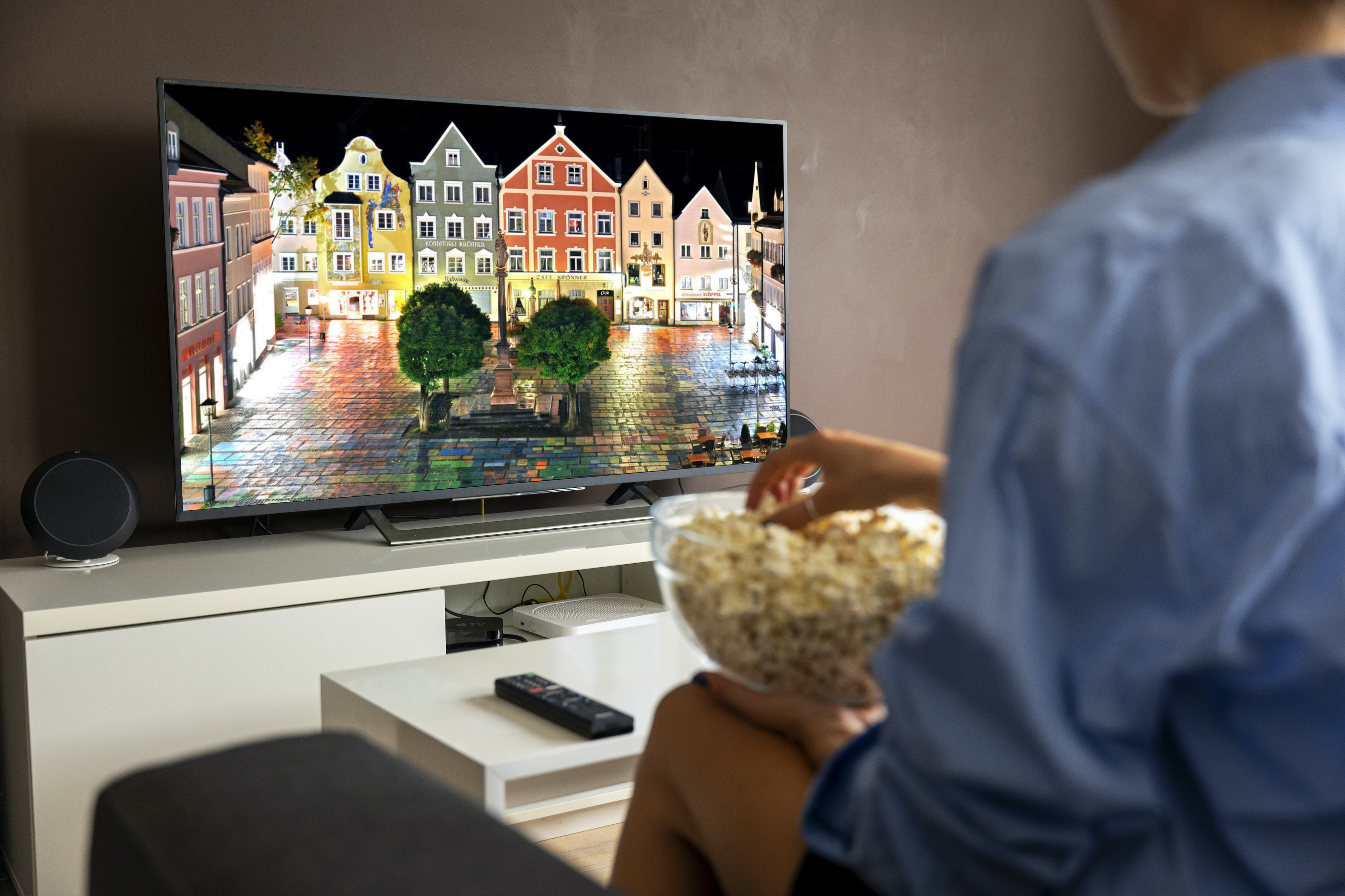Smart TV on the white TV unit beside the woman eating popcorn_969156914-kommunalwahl-2020-weilheim-sind-buergermeisterkandidaten-in-weilheim-2uNyk0QtRrfe